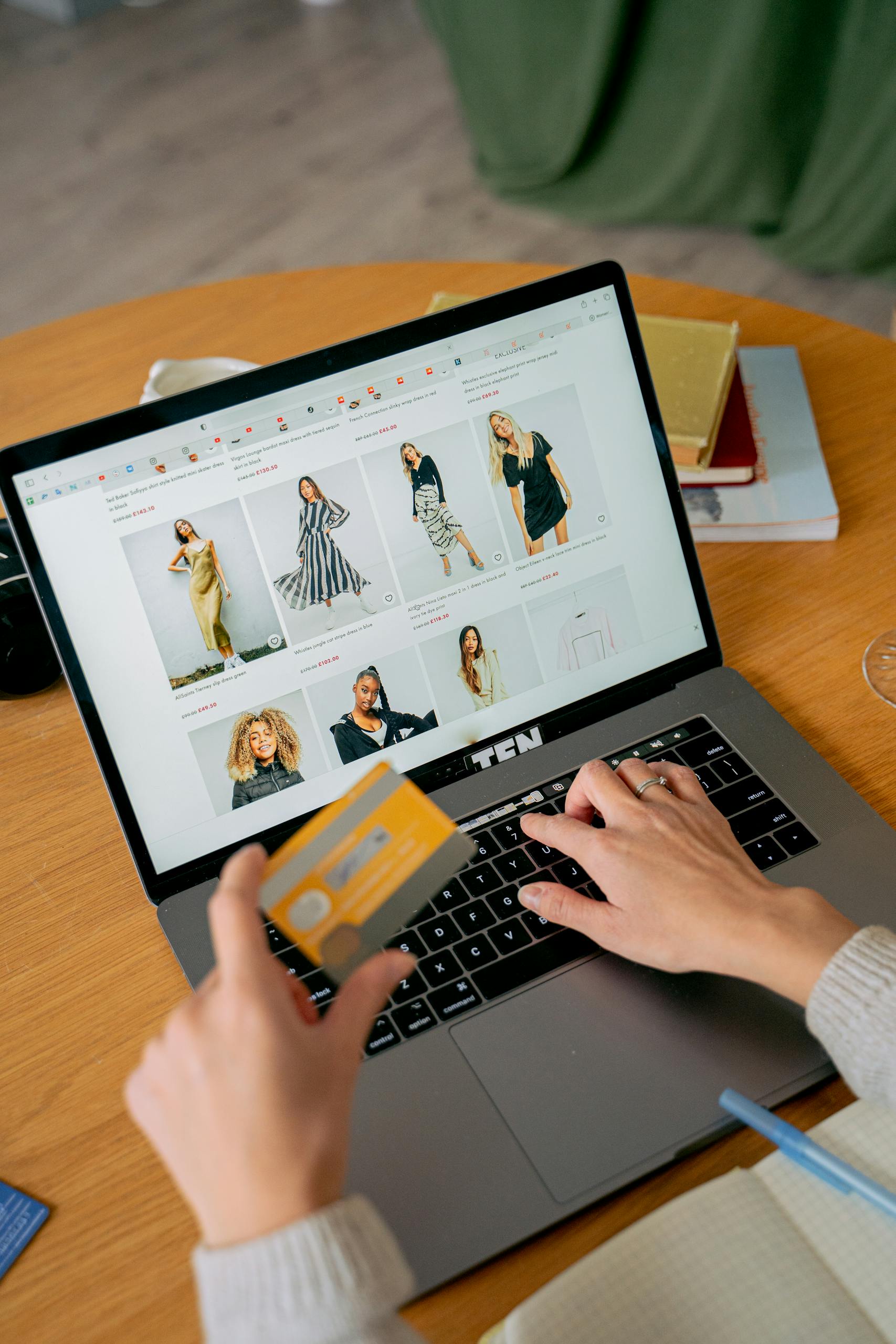 JuicyCRM for Ecommerce Stores | A woman makes an online purchase using a credit card on her laptop, browsing an online fashion store.