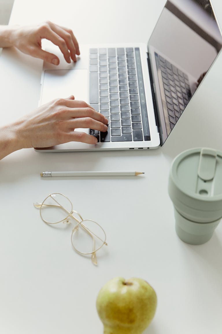 Minimalist home office desk with a laptop, coffee cup, and apple, creating a clean and modern work environment.